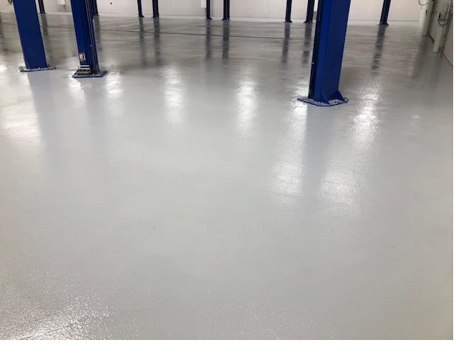 Light gray epoxy floor in an automotive shop with lift columns